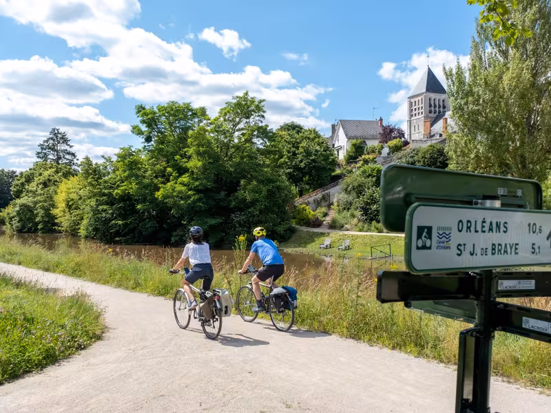 2 cyclistes sur le canal d'Orléans à vélo à l'entrée d'un village
