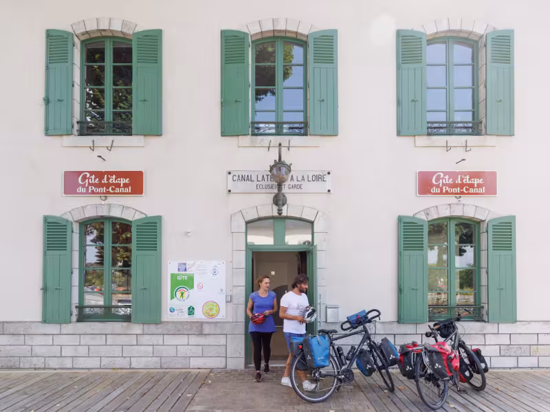 Cyclistes sortant du gîte d'étape Accueil Vélo du pont canal de briare